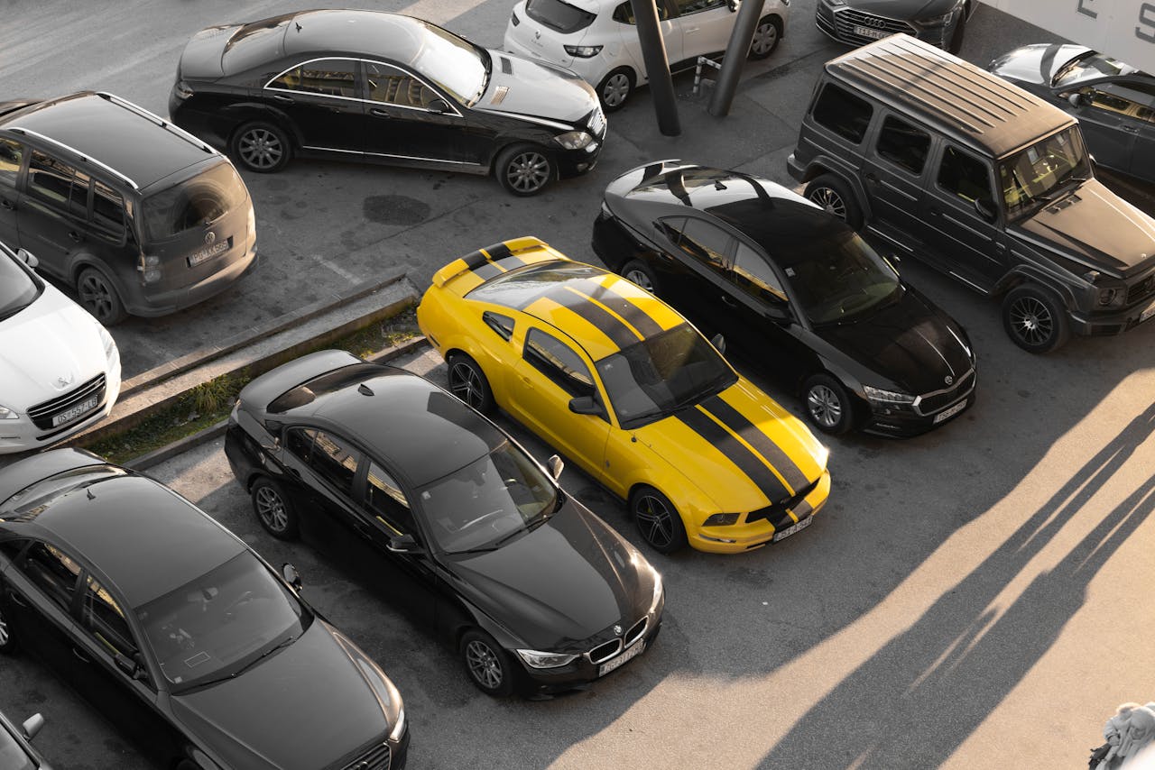 hero-img-01 Top view of various cars parked in a parking lot, featuring a yellow sports car.